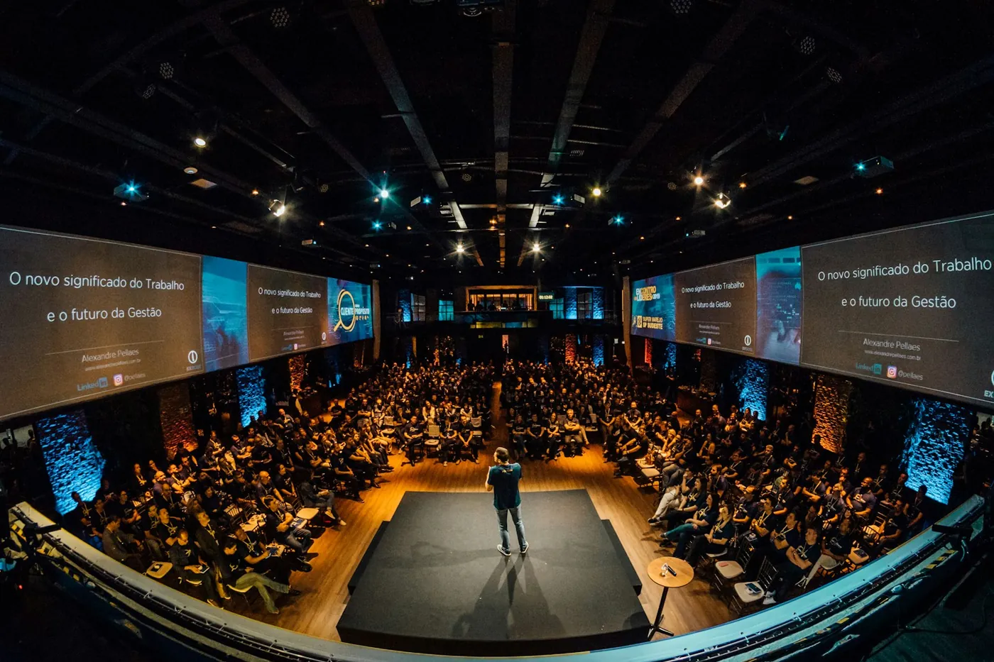 A speaker addressing a seated audience in a large hall (illustrative)